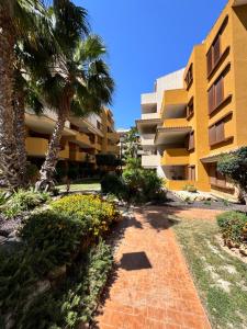 a building with palm trees and a walkway at La Recoleta Residence Punta Prima in Torrevieja