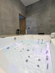 a large white bath tub in a bathroom at My'Deting - Jacuzzi in Roanne +19 photos