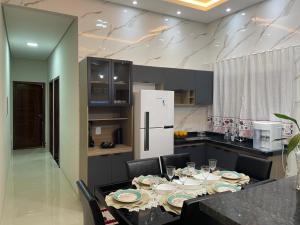 a kitchen with a table with chairs and a refrigerator at Casa Suítes Beach in Vilhena