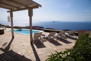 a group of chairs sitting on a patio next to a pool at Villa with infinity pool and exceptional sea view in Kithnos