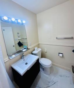 bagno con servizi igienici, lavandino e specchio di Foghorn Harbor Inn a Los Angeles