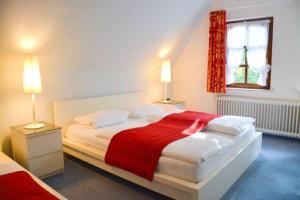 a bedroom with a large white bed with a red blanket at Landhaus Fillerberg in Wildeshausen