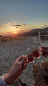 dos personas sosteniendo vasos de cerveza frente a la puesta de sol en Dana Tower Hotel en Ḑānā