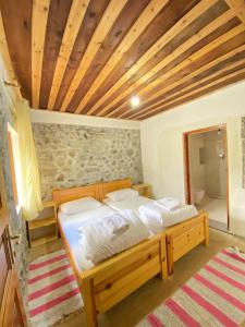 sypialnia z łóżkiem i drewnianym sufitem w obiekcie Rupa Guest House w mieście Theth