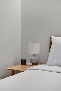 a bed with a lamp and a nightstand with a white bed at Modern Lifestyle Loft with View - Zuni Lofts in Denver