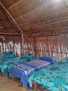 um grupo de três camas numa cabana de palha em Discovery Gunayar em Waisalatupo