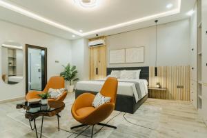 a bedroom with a bed and two orange chairs at 3 bedroom Greys Apartment Lifecamp Abuja in Tungan Daudu