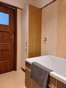 uma casa de banho com banheira e uma porta de madeira em Turkusowa Apartament em Szczecin