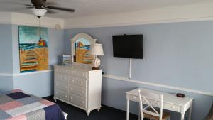 1 dormitorio con cama, escritorio y TV en la pared en Coral Sands Inn, en Ormond Beach