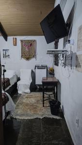uma sala de estar com um sofá e uma televisão de ecrã plano em Dom Jaime - Guest House em Pirenópolis
