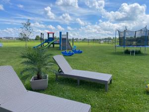 a park with a playground with two chairs and a slide at BALTICO Domki Letniskowe in Sarbinowo