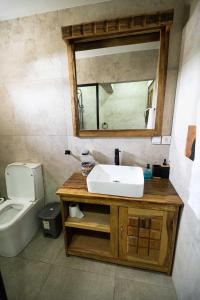a bathroom with a sink and a mirror and a toilet at La Teranga Apartament in Toubakouta