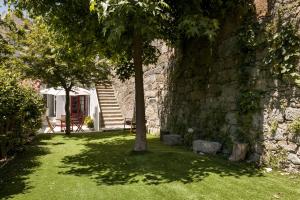 a stone wall with a tree in a yard at Almada Charm Suites & Apartments in Porto