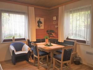 ein Esszimmer mit einem Tisch, Stühlen und Fenstern in der Unterkunft Modern apartment with garden near the Petzen ski area in Eberndorf Carinthia in Eberndorf