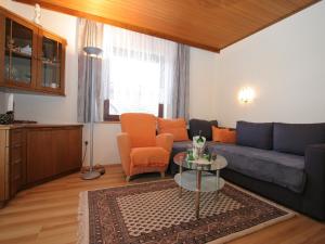 sala de estar con sofá azul y sillas de color naranja en Modern apartment with garden near the Petzen ski area in Eberndorf Carinthia en Eberndorf