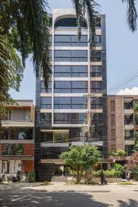 un edificio alto con árboles delante de él en First Class Hotel by 5 Host, en Medellín