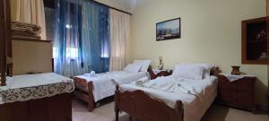 una habitación con tres camas y una ventana en Guest House Makos, en Gjirokastra