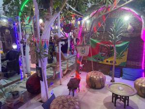 una habitación con una tienda de campaña con sillas, mesas y luces en peace garden hostel & camp en Luxor