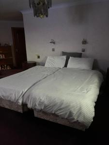a large white bed with white sheets and pillows at Ruthven in Stevenston