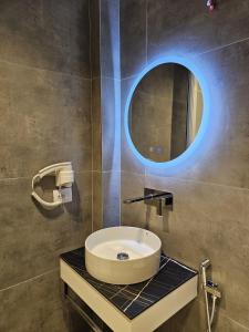 a bathroom with a sink and a round mirror at Diol Hotel Ksamil in Ksamil
