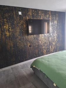 1 dormitorio con 1 cama y pared con TV en Safta Apartament 3, en Cîmpulung