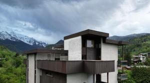 a building with a balcony with mountains in the background at Duplex St Gervais rooftop - 500m des télécabines in Saint-Gervais-les-Bains