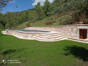 eine steinerne Wand mit einer Treppe auf einem Grasfeld in der Unterkunft Graceful Holiday Home in Acqualagna with Swimming Pool in Acqualagna