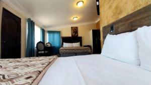 a bedroom with a large bed with white sheets at Hotel Don Felipe Aeropuerto in Guatemala