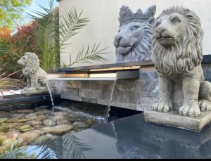 two statues of lions standing next to a pond at Lanstone House in Chipping Norton