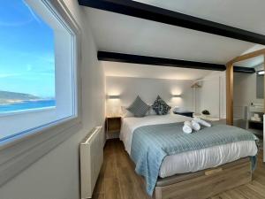 a bedroom with a large bed with a large window at Öspede Casa Totoia- Malpica de Bergantiños, Costa da Morte in Malpica