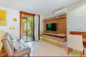 un soggiorno con un divano e una televisione di CS15 BANGALÔ DUPLEX frente ao mar Itacimirim a Camassari