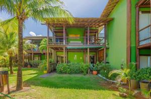 una casa verde con balcone e palme di CS15 BANGALÔ DUPLEX frente ao mar Itacimirim a Camassari