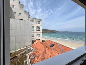 a view of a building and the beach from a window at Öspede Casa Totoia- Malpica de Bergantiños, Costa da Morte in Malpica