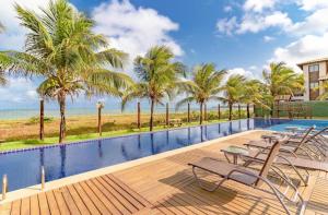 una piscina del resort con sedie, palme e spiaggia di CS15 BANGALÔ DUPLEX frente ao mar Itacimirim a Camassari Altre 20 foto