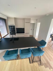 a kitchen with a black table and blue chairs at Vue Mer Très belle plage à pied Maison proche Lesconil Loctudy in Loctudy +14 photos