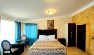 ein Hotelzimmer mit einem Bett, einem Schreibtisch und einem Fenster in der Unterkunft Hotel Don Felipe Aeropuerto in Guatemala