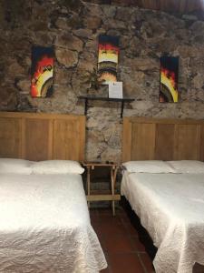 a room with two beds and a stone wall at Hotel San Pancho in Real de Catorce