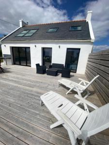 a deck with chairs and a bench and a house at Vue Mer Très belle plage à pied Maison proche Lesconil Loctudy in Loctudy
