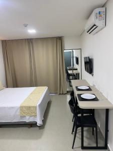 a hotel room with a bed and a table and chairs at Apartamento próximo a praia no Tramonto bessa in João Pessoa +2 photos