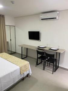 a room with a table and chairs and a television at Apartamento próximo a praia no Tramonto bessa in João Pessoa