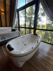 a bath tub in a room with a large window at Taboo Refúgio in Nova Petrópolis +82 photos