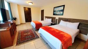 Cette chambre comprend deux lits et une télévision. dans l'établissement Hotel Don Felipe Aeropuerto, à Guatemala