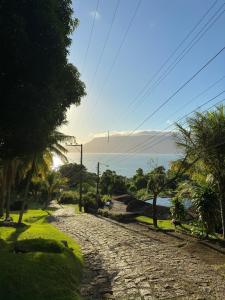 een geplaveide weg met palmbomen en de oceaan bij Ilhabela Chalés in Ilhabela