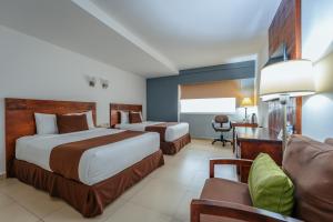 a hotel room with two beds and a desk at Hotel La Venta Inn Villahermosa in Villahermosa