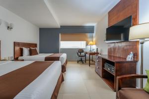 Habitación de hotel con 2 camas y escritorio en Hotel La Venta Inn Villahermosa, en Villahermosa