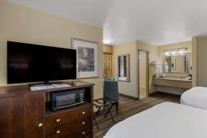 a hotel room with a bed and a flat screen tv at Best Western Cottage Grove Inn in Cottage Grove