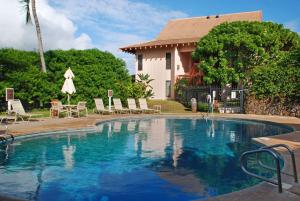 a swimming pool with chairs and a house at Aston At Poipu Kai in Koloa