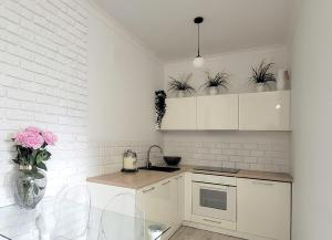 a kitchen with white cabinets and potted plants at Warsaw Concierge Opera Apartment in Warsaw