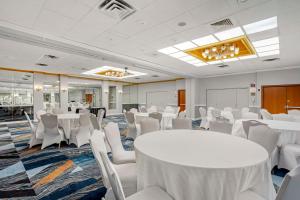Best Western Rutgers University Hotel في إيست برونزويك: قاعة اجتماعات مع طاولات بيضاء وكراسي بيضاء