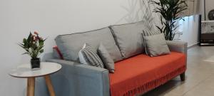 a grey couch with an orange blanket and pillows at Conforto e Privacidade no Roteiro do Vinho in São Roque